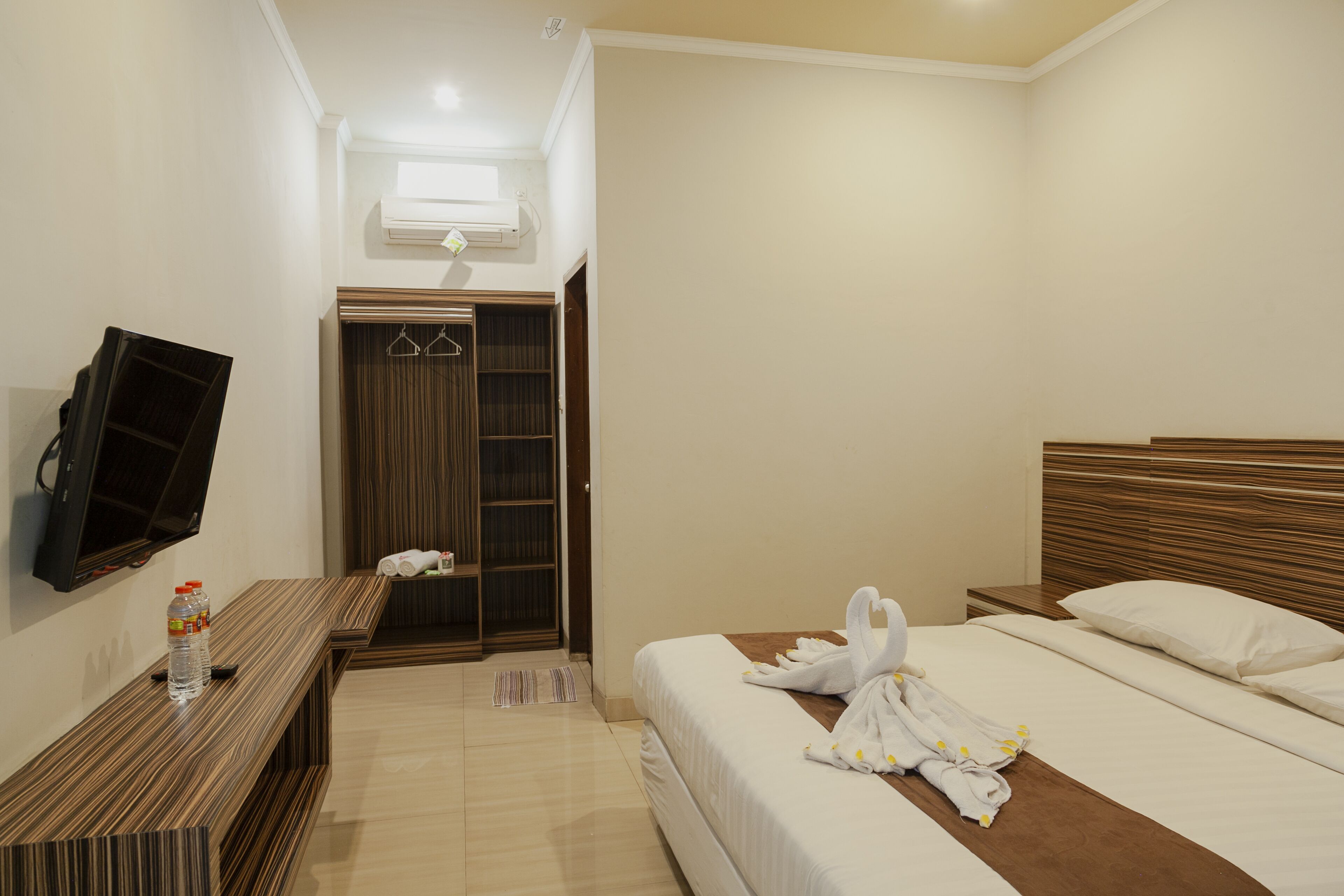 A hotel room with a bed, a TV, a wardrobe, and a bathroom.