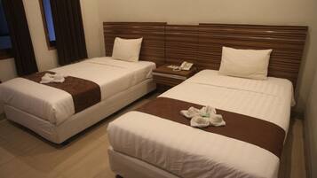 Two single beds with wooden headboards, a bedside table with a phone, and a brown accent pillow.
