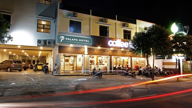 A hotel with a sign for "Palapa Hotel" and a coffee shop across the street. - Palapa Hotel (Mataram)