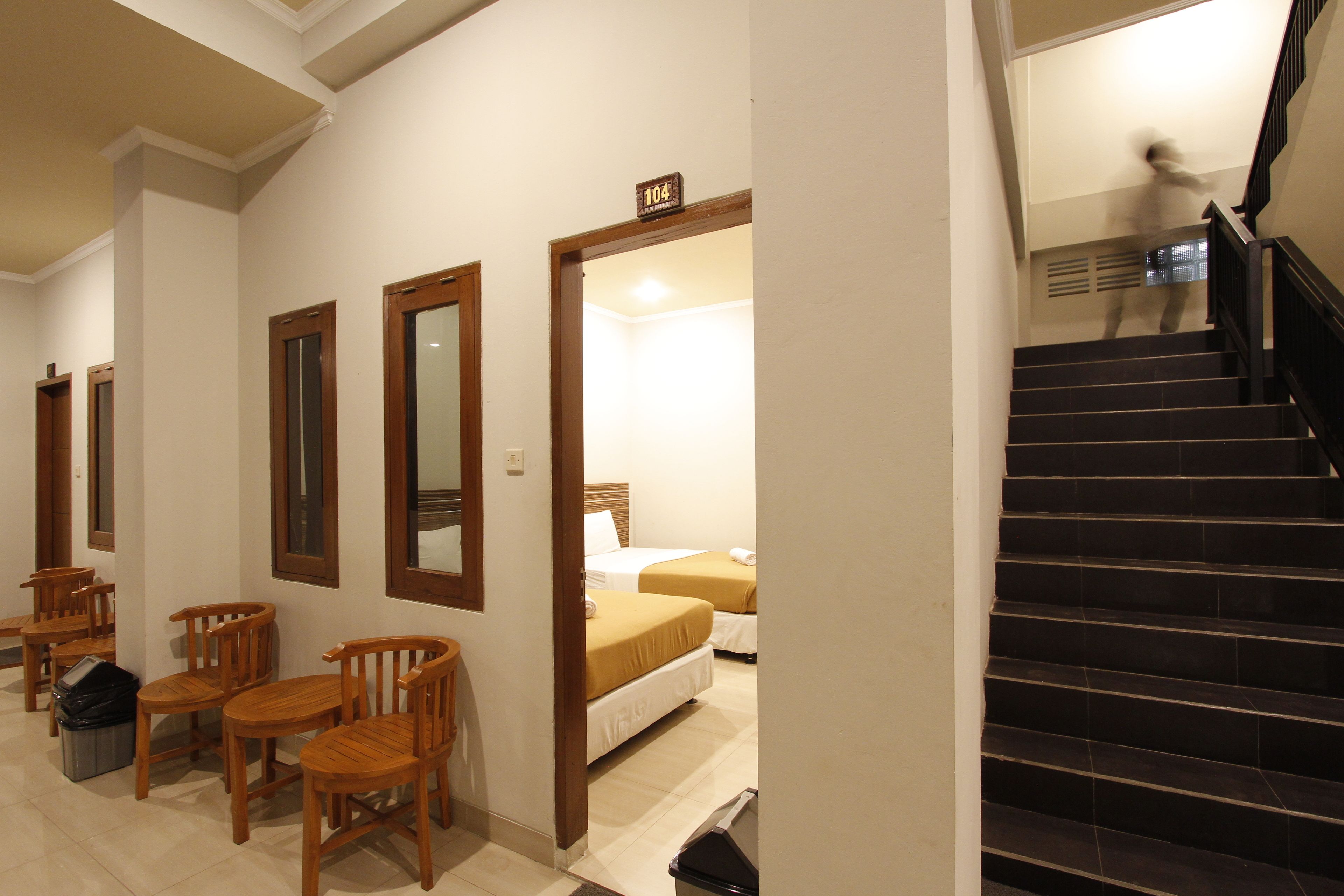 Une chambre d’hôtel avec un lit, un bureau et une chaise. Un escalier mène à un autre étage.
