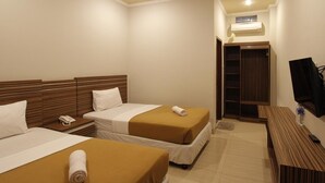 A hotel room with two beds, a wooden headboard, a TV, a desk, and a wardrobe. - Palapa Hotel (Mataram)