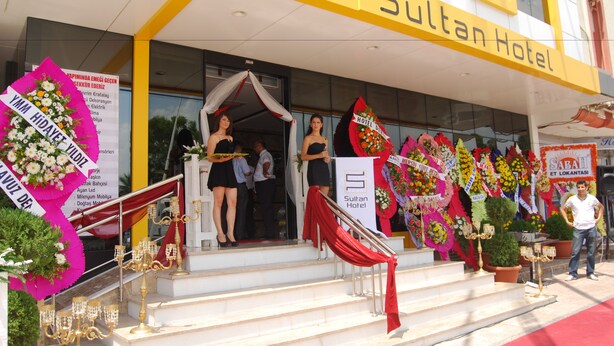 The entrance of Sultan Hotel with steps leading up to the entrance, decorated with flowers and a red drape. - Sultan Hotel (Mersin)