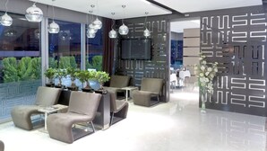 A modern lobby with seating, a TV, and decorative plants. - Sultan Hotel (Mersin)