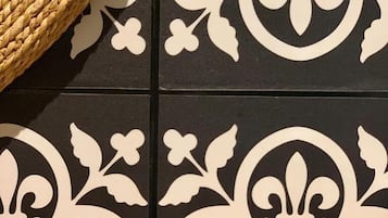 Une partie du sol est recouverte de carreaux noirs et blancs formant un motif, et un panier tressé se trouve sur la gauche.