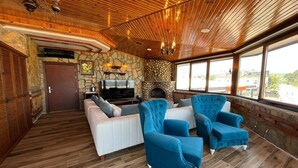 A spacious living area with a stone fireplace, wooden ceiling, and large windows. - Olinda Hotel Agva (Sile)