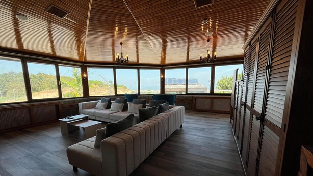 A spacious living room with a large sofa, a coffee table, and a view of the beach through large windows. - Olinda Hotel Agva (Sile)