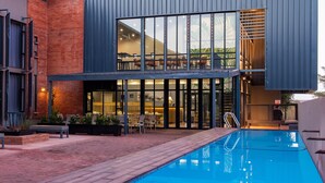 A modern building with a pool, large windows, and outdoor seating. - Urban Hotel Kathu (Kathu)
