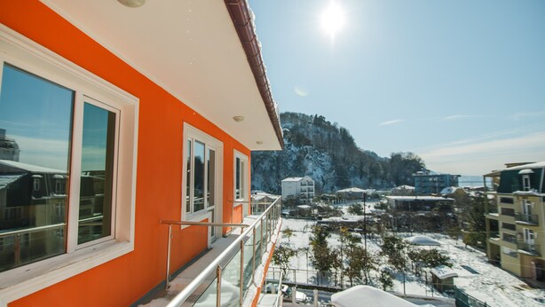 A modern building with large windows and a balcony overlooking a snowy landscape with buildings and a mountain in the background. - Hotel Egrisi (Batumi)