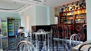 A bar area with seating, a refrigerator, and shelves with bottles. - Hotel Egrisi (Batumi)