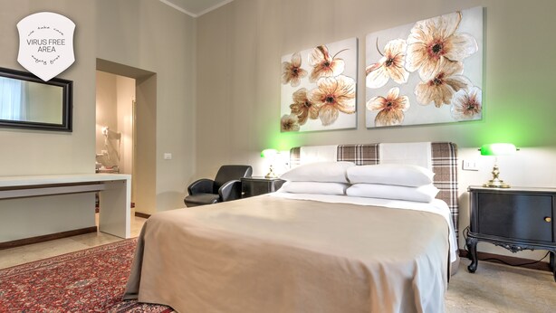 A hotel room with a large bed, a desk, a chair, and artwork on the wall. - Ramé Suites (Bergamo)