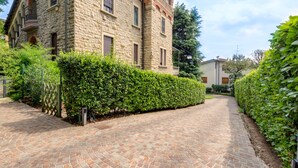 A stone building with a paved driveway and a well-maintained hedge. - Ramé Suites (Bergamo)