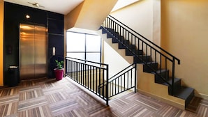 A modern interior with a staircase, elevator, and patterned flooring. - Quds Express Hotel (Jakarta)