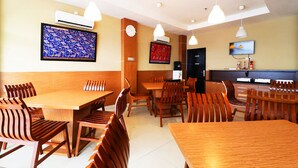 A restaurant with wooden tables and chairs, air conditioning units, and wall-mounted televisions. - Quds Express Hotel (Jakarta)