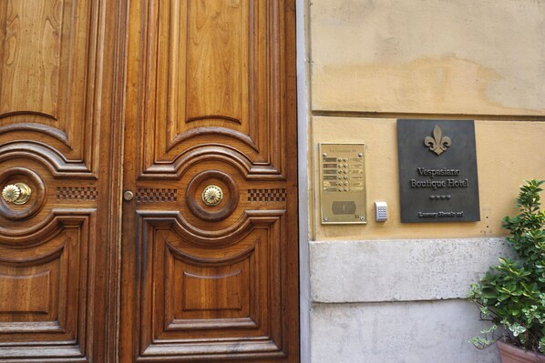 A wooden double door with a brass handle and a plaque reading "Vespasiano Boutique Hotel." - Hotel Vespasiano (Rome)