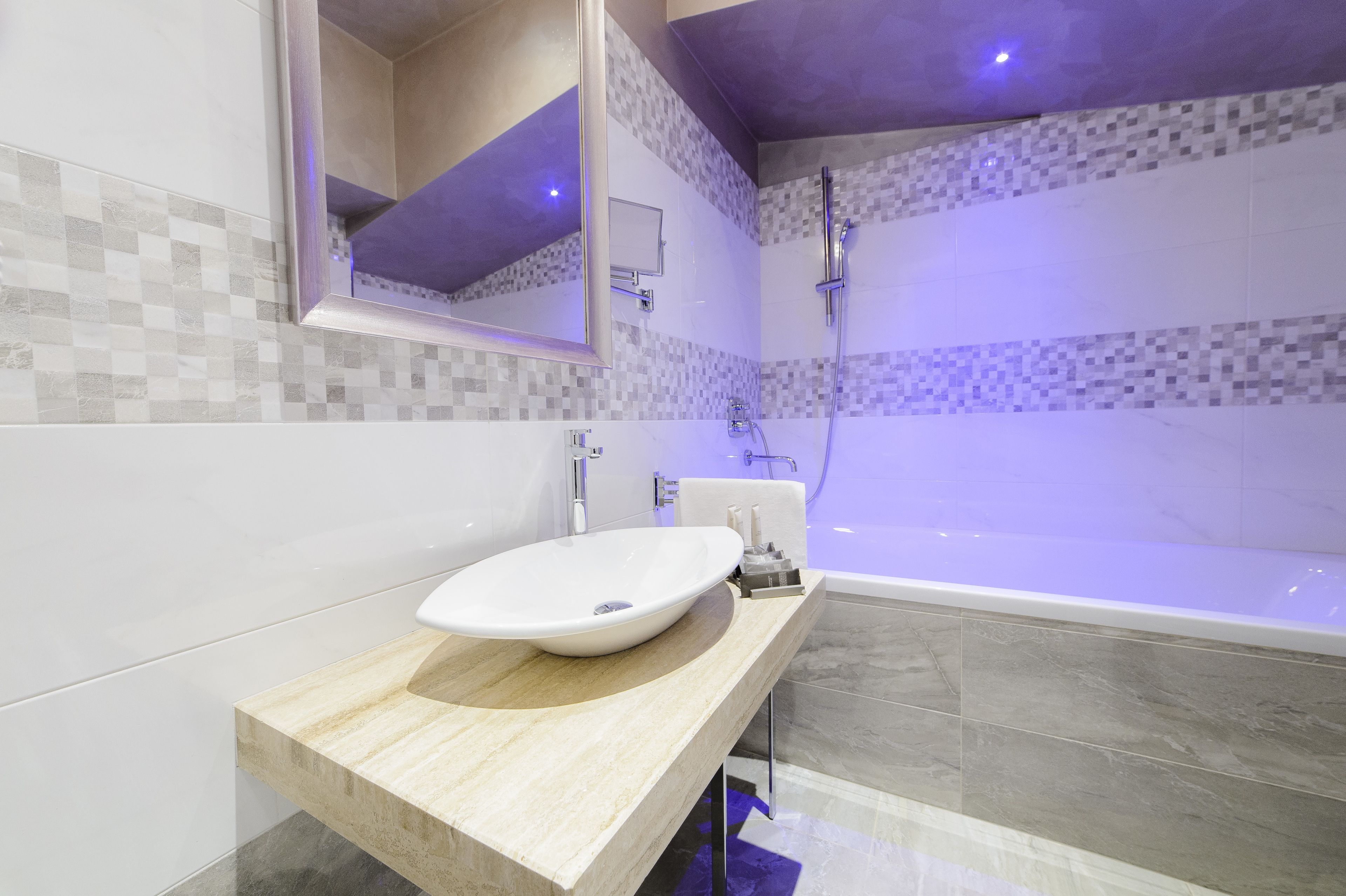 A modern bathroom with a large bathtub, a sink with a marble countertop, and a tiled shower area.