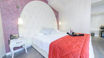 A modern bedroom with a large bed, a bedside table with a phone and a lamp, and a red blanket.