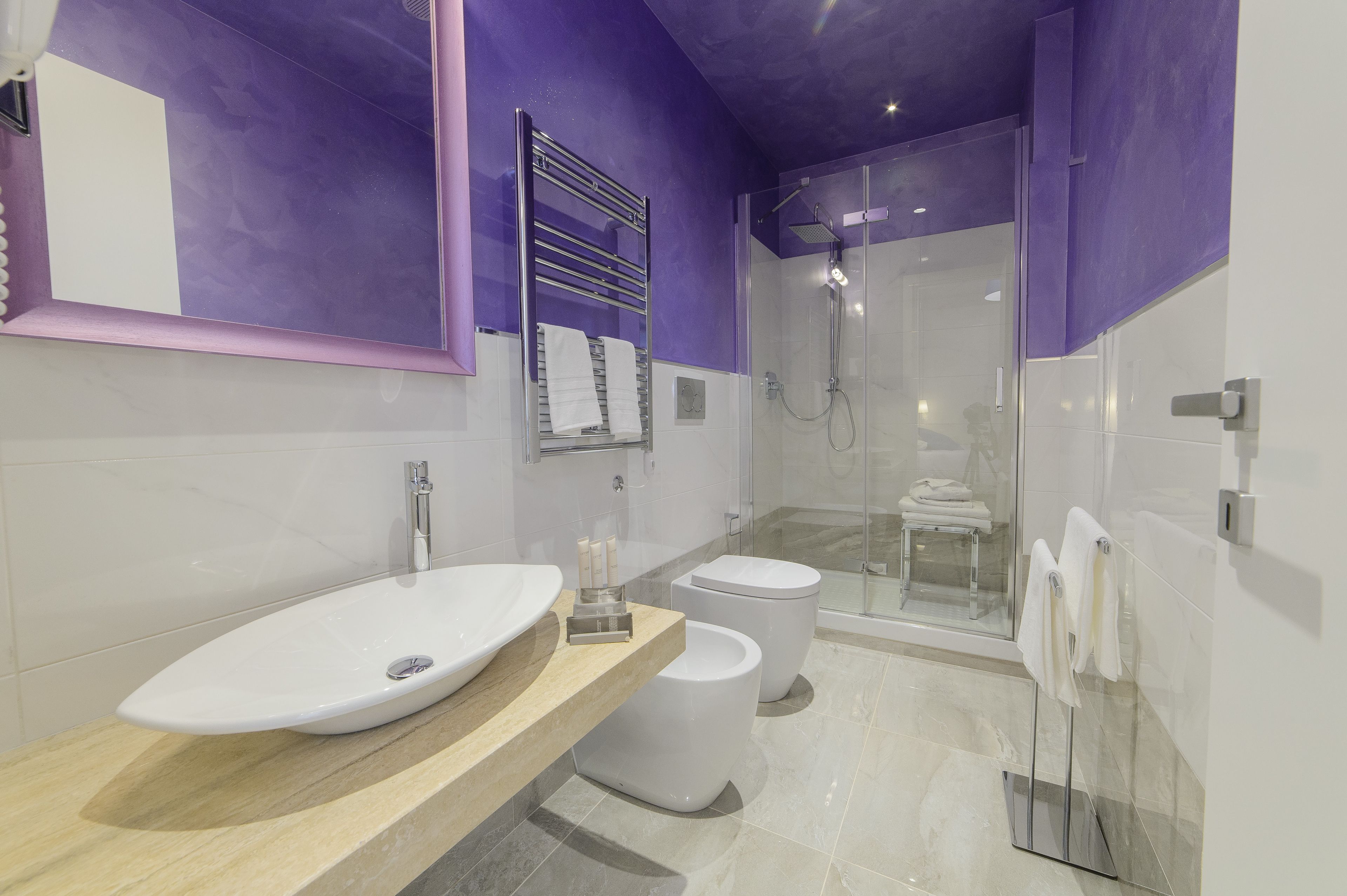 A modern bathroom with a large sink, two toilets, and a glass-enclosed shower area.