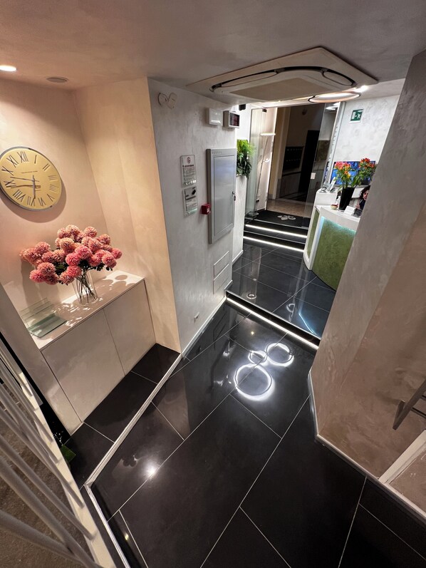 Un moderno vestíbulo de hotel con mostrador de recepción, un reloj y una escalera.