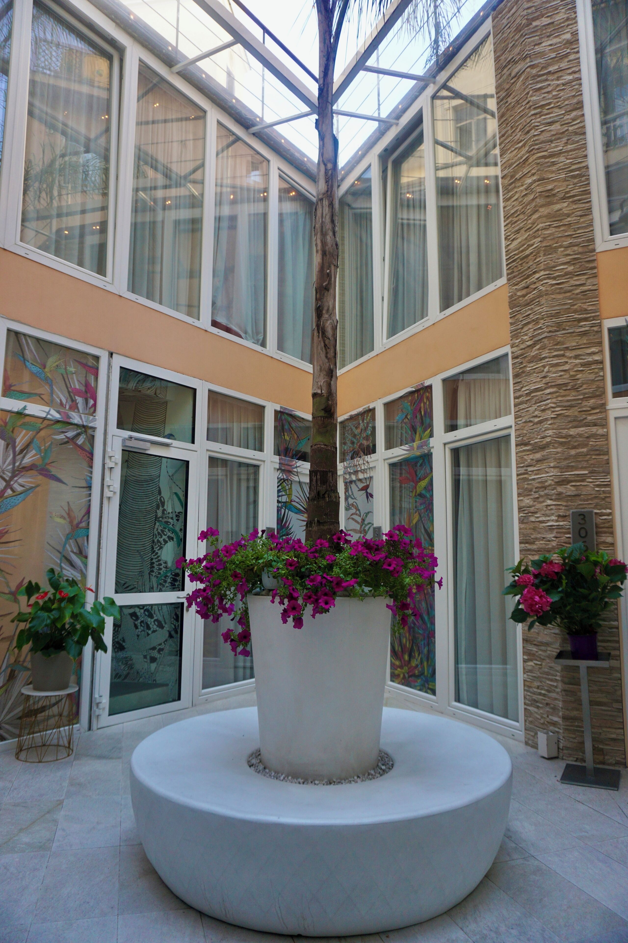 A modern atrium with a central planter, large windows, and a stone accent wall.
