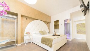 A modern bedroom with a large bed, a bedside table with a lamp, and a view of the outside through a glass door. - Hotel Vespasiano (Rome)