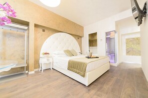 A modern bedroom with a large bed, a bedside table with a lamp, and a view of the outside through a glass door. - Hotel Vespasiano (Rome)