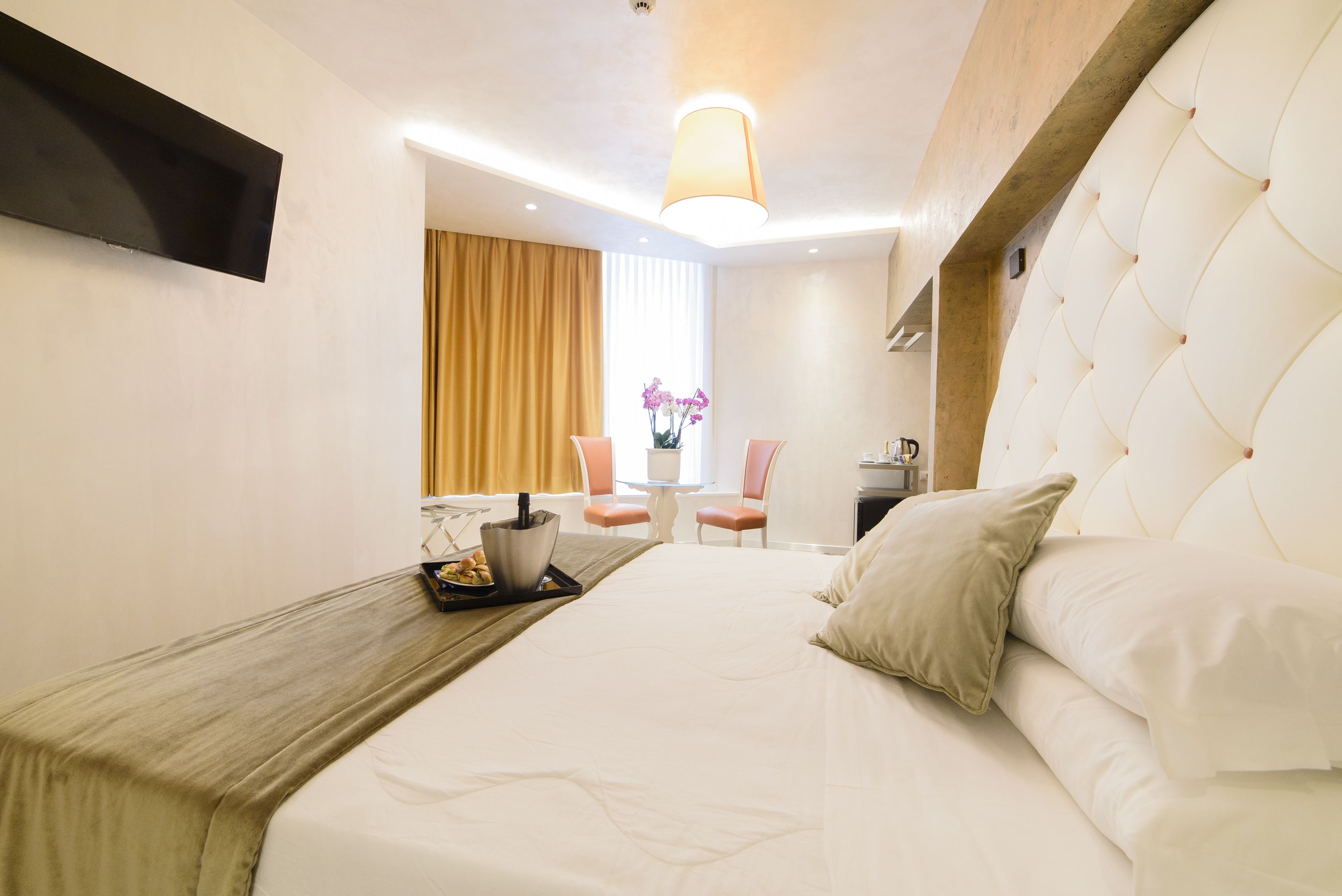 A hotel room with a large bed, a desk with a laptop, a chair, and a window with curtains.