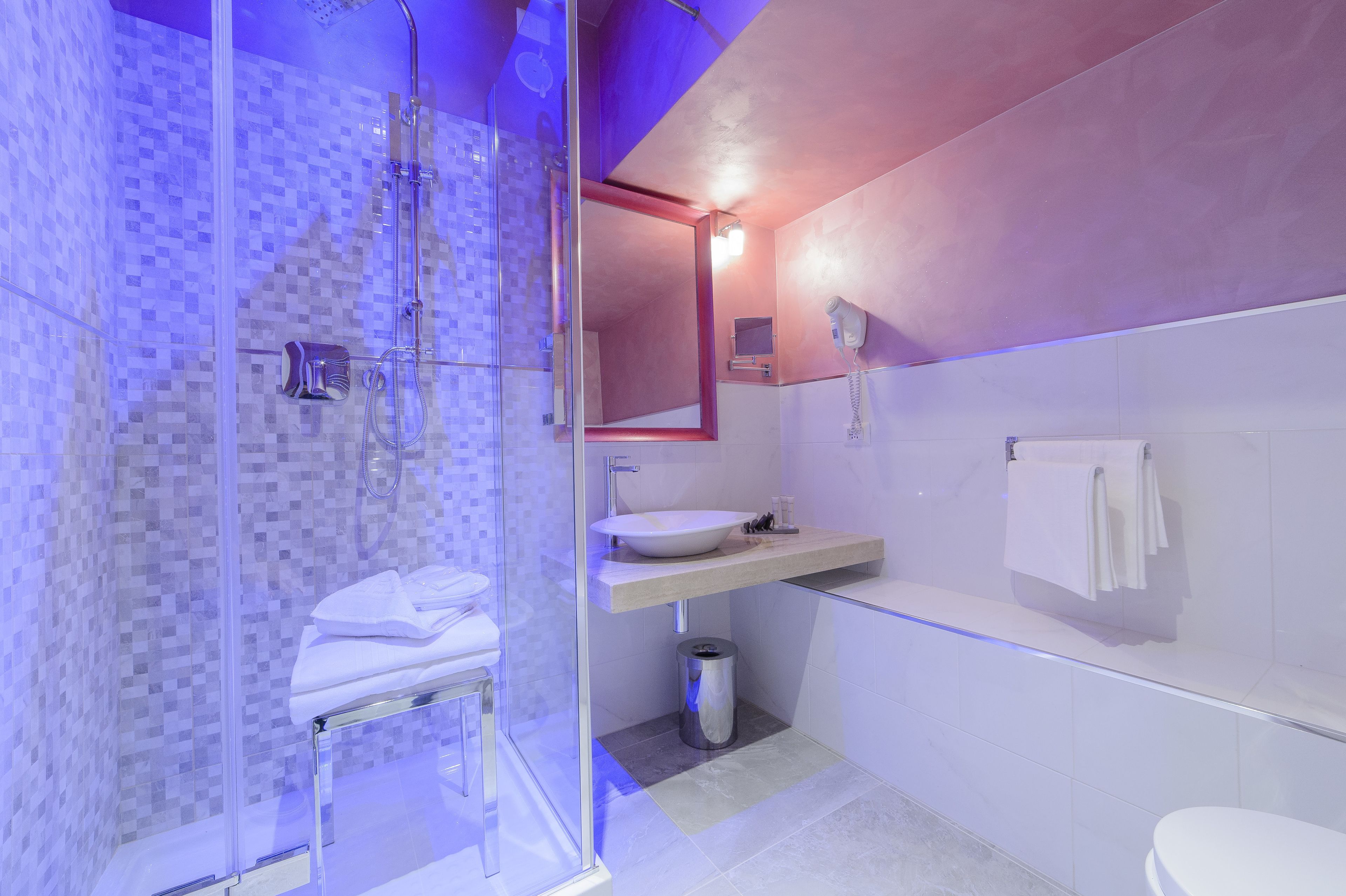 Un baño moderno con cabina de ducha de vidrio, un lavamanos blanco y un espejo sobre él.