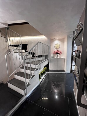 A modern staircase with metal railings and black steps leading to a landing. - Hotel Vespasiano (Rome)