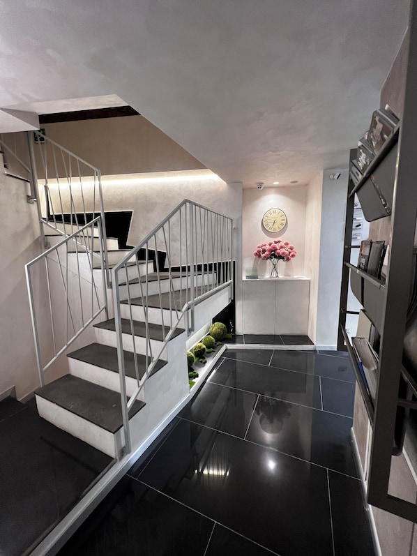 A modern staircase with metal railings and black steps leading to a landing. - Hotel Vespasiano (Rome)
