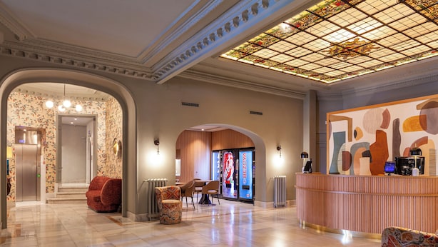 A lobby with a reception desk, seating area, and a staircase leading to another floor. - Hotel Mediodia (Madrid)