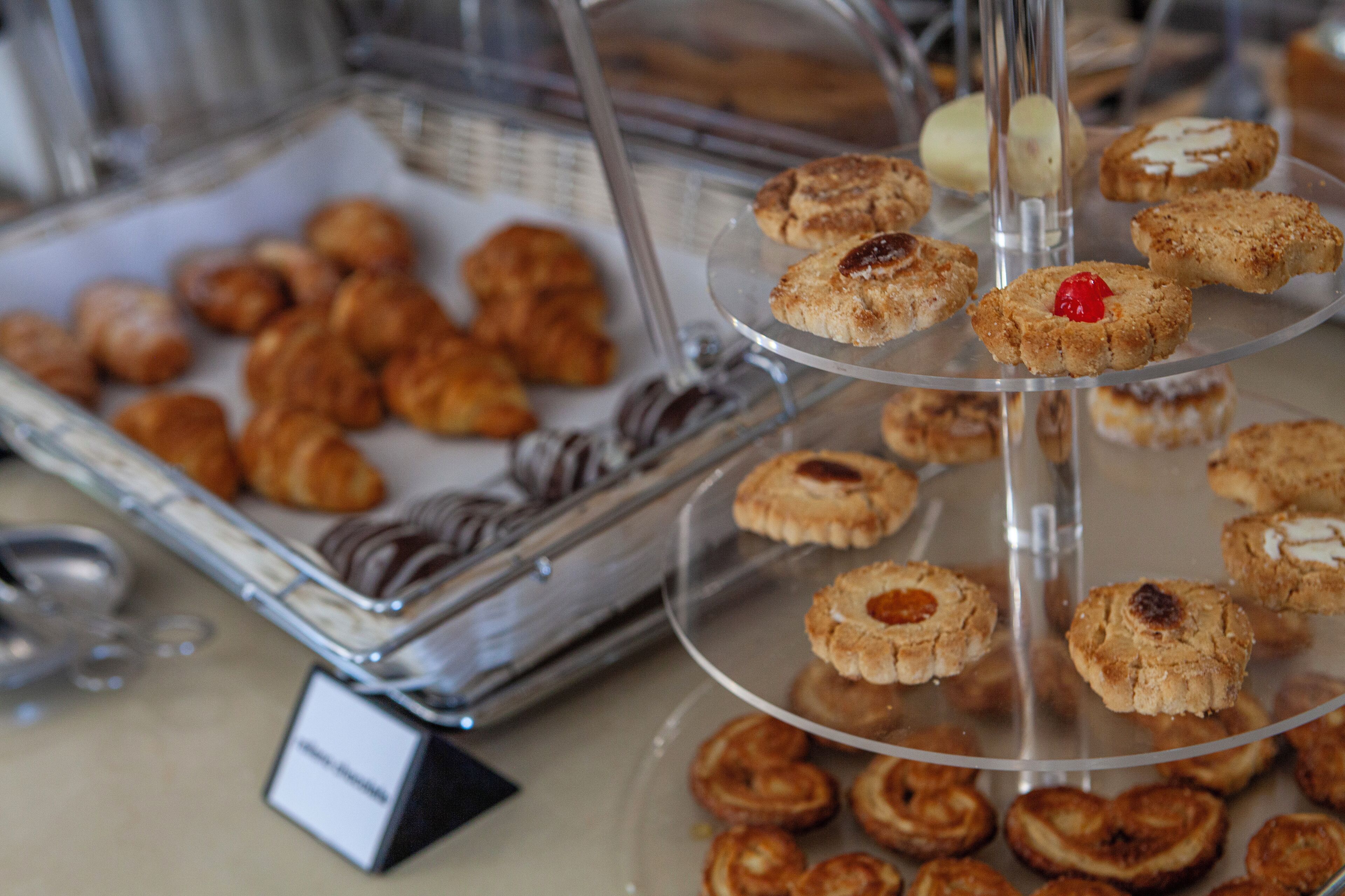 Diversos doces e pastéis expostos em um suporte de vidro de vários andares.