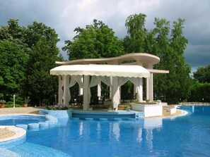 Un'area piscina con un gazebo, immersa nel verde.