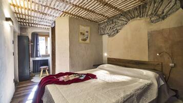 A bedroom with a wooden headboard, a bed with a white quilt, a red throw blanket, and a framed picture on the wall.