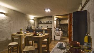 Un'accogliente zona pranzo in stile rustico, con mobili in legno, un tavolo apparecchiato per due e una cucina sullo sfondo.