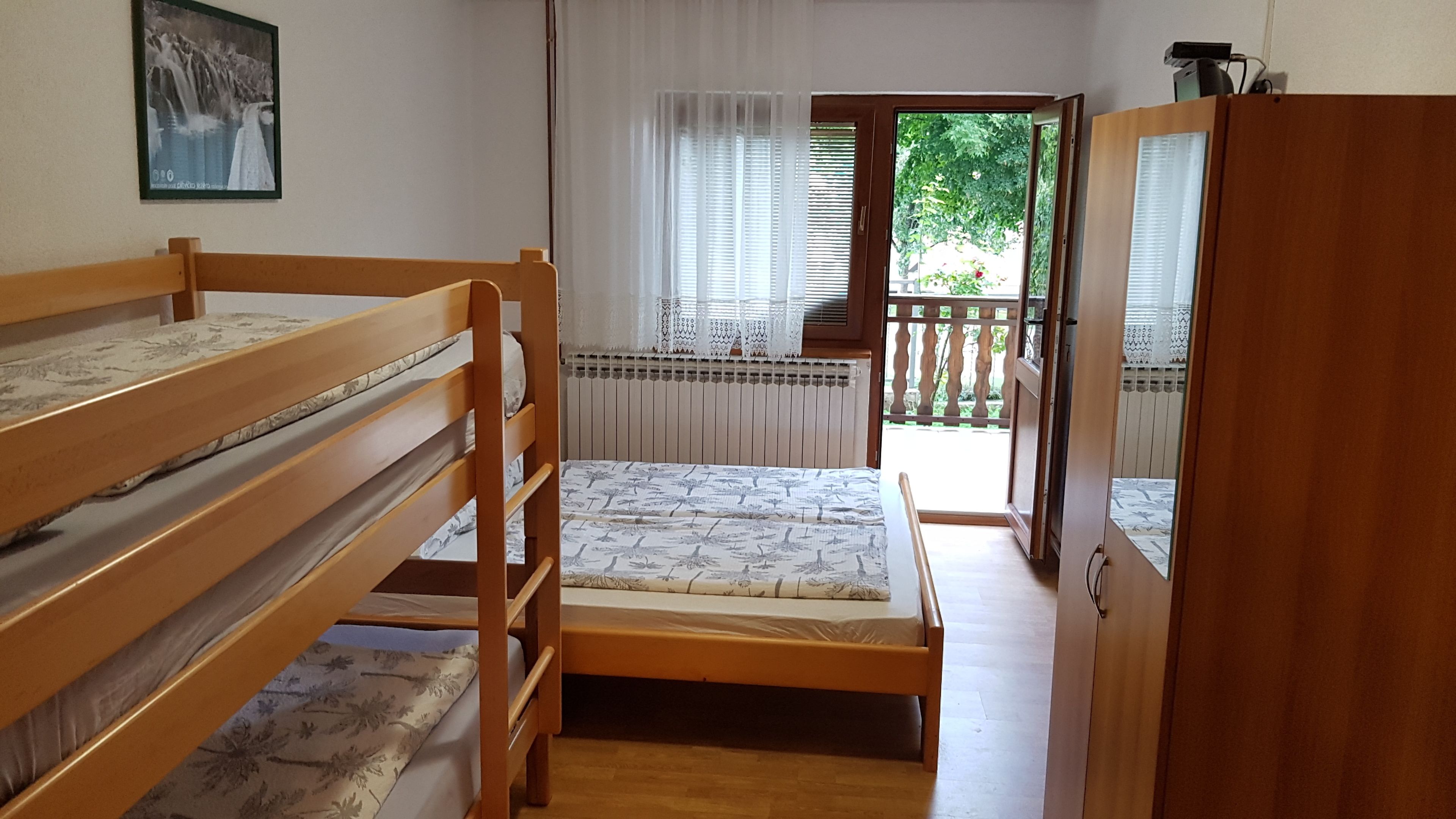 Una habitación con literas, un radiador, una ventana con cortinas y vistas a un balcón.