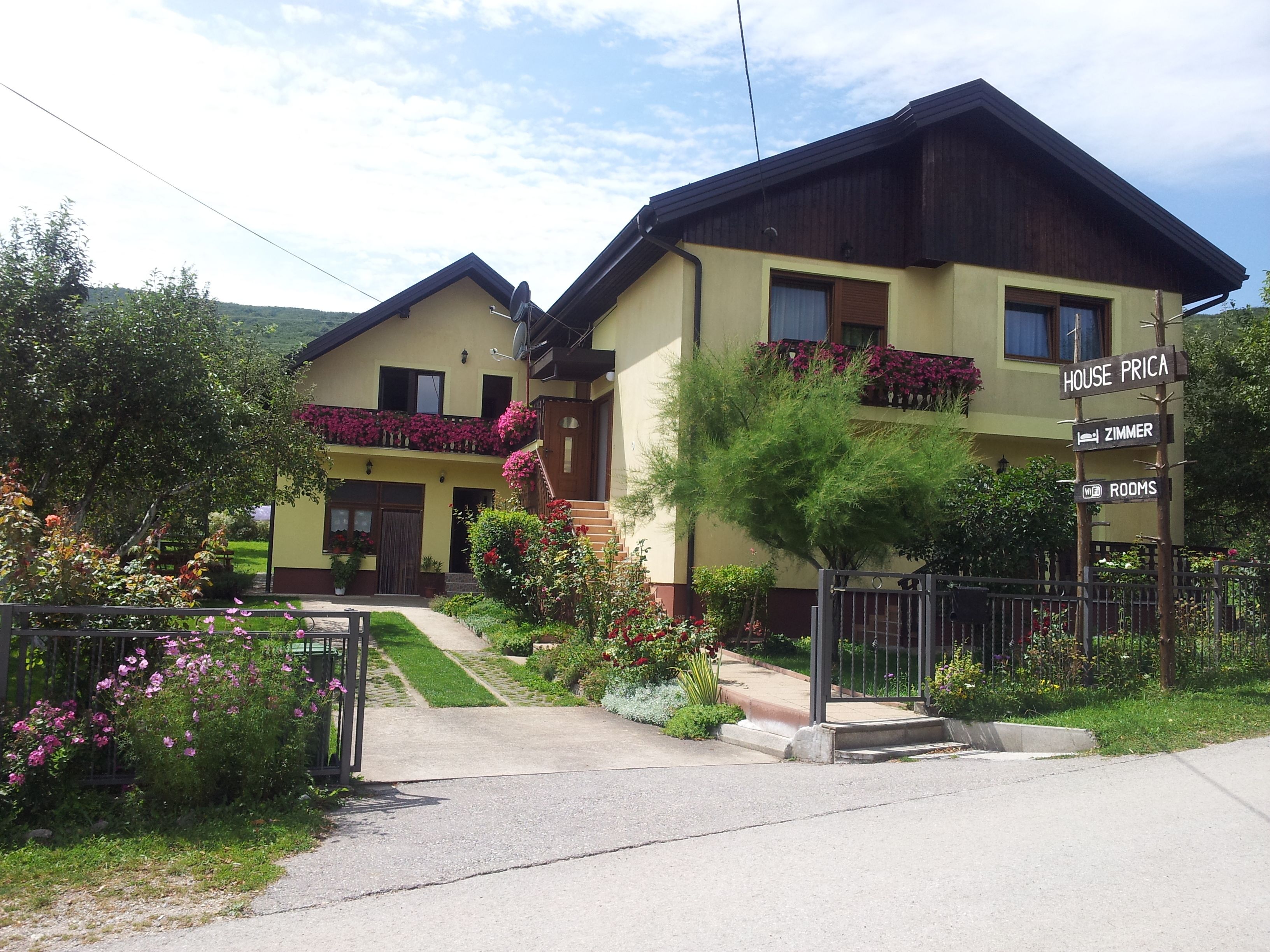 Una casa de dos pisos con un letrero que indica 'HOUSE PRICA' y 'ZIMMER ROOMS'.