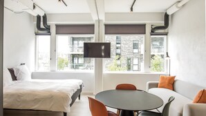 Un dormitorio moderno con cama, una mesa de comedor con sillas y un sofá.