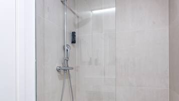 Una ducha moderna con puerta de cristal, cabezal de ducha manual y grifo empotrado.