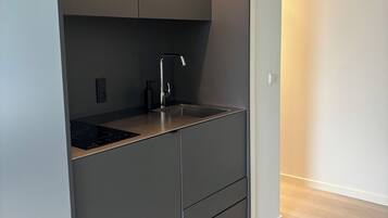 Una cocina moderna con armarios empotrados, un lavamanos de acero inoxidable y una placa de inducción negra.