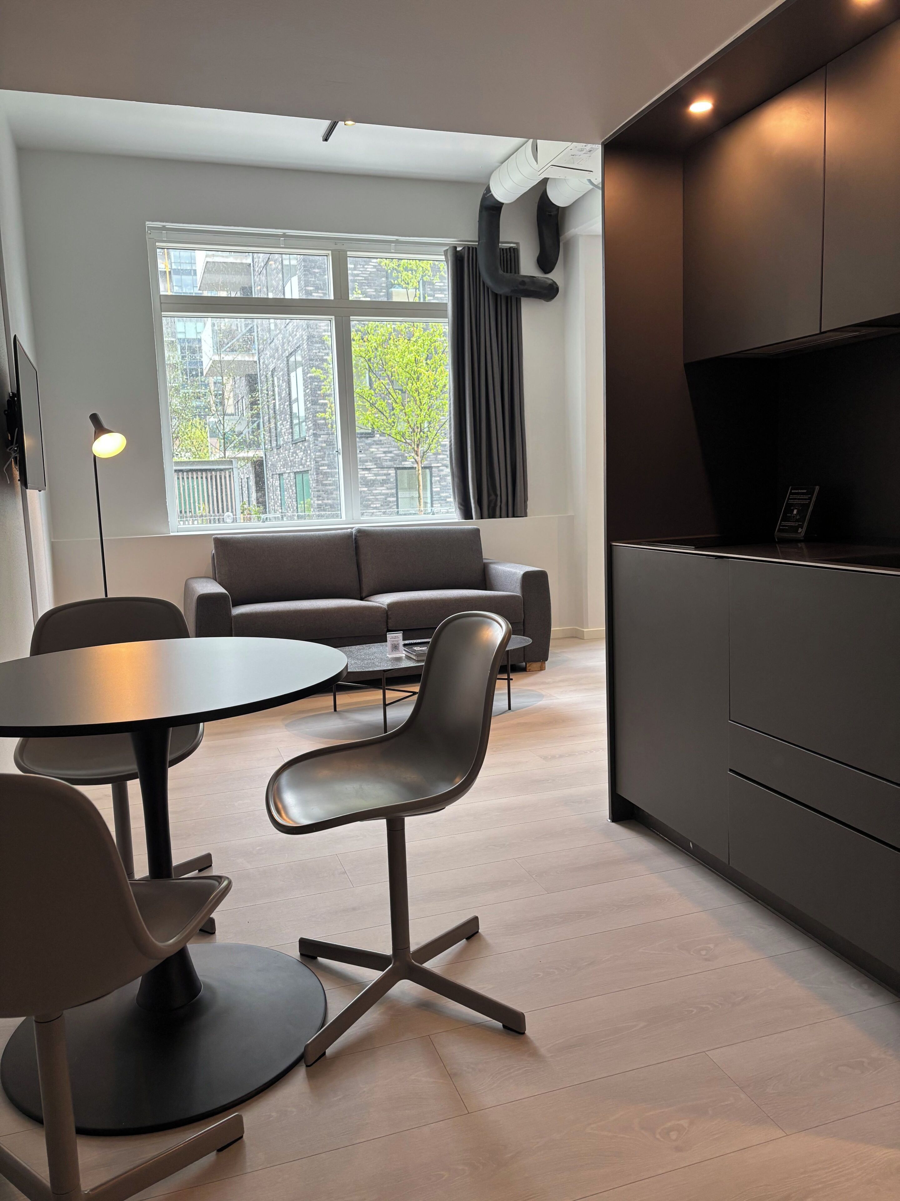 Un interior moderno con sofá, mesa de comedor, sillas y zona de cocina.
