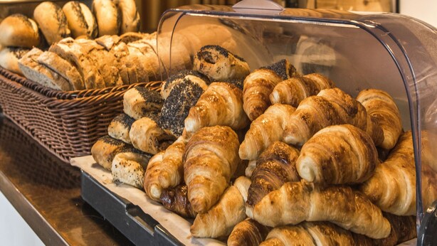 Una vitrina de panadería con distintos tipos de pan y pasteles.
