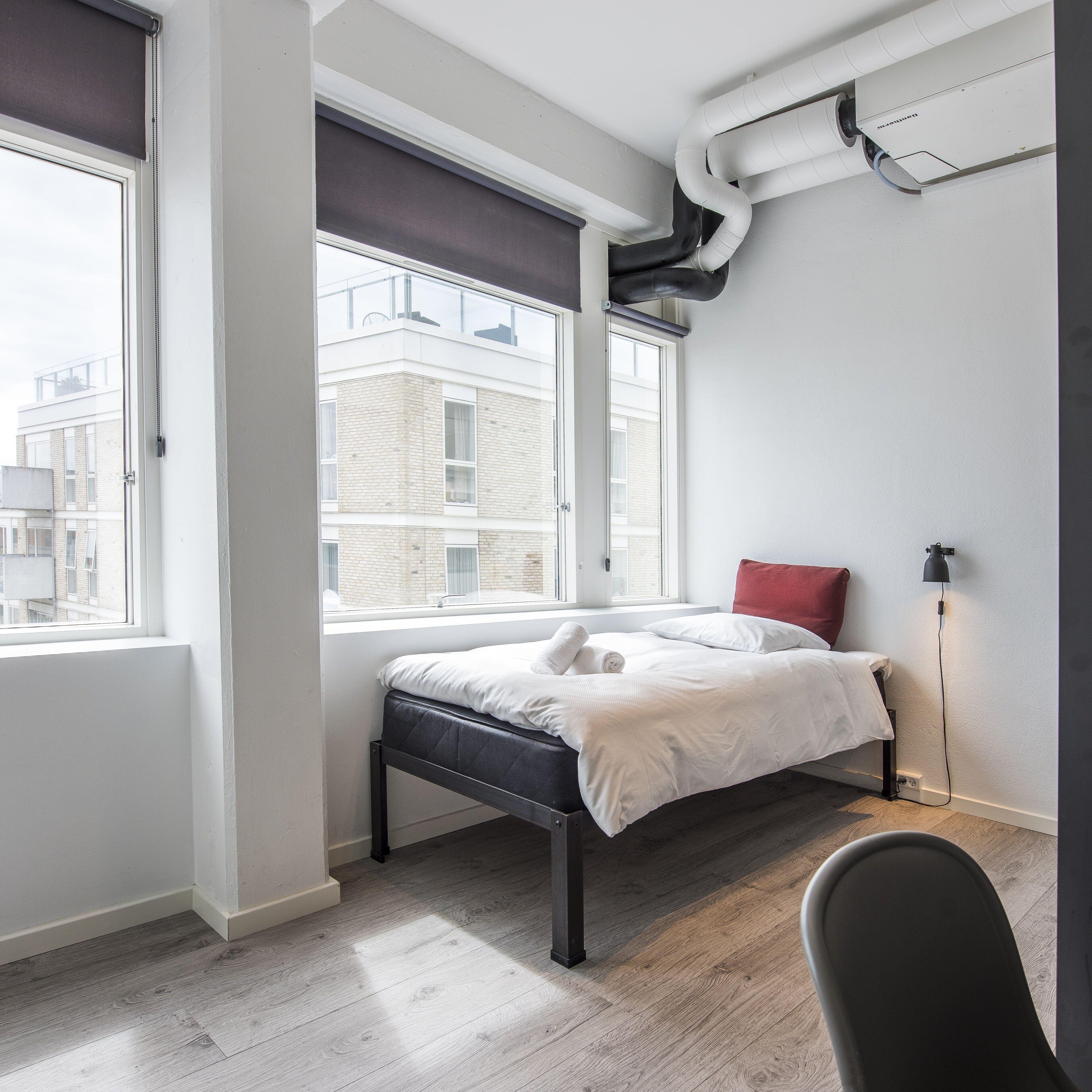 Un dormitorio moderno con una cama, un ventanal y un radiador.