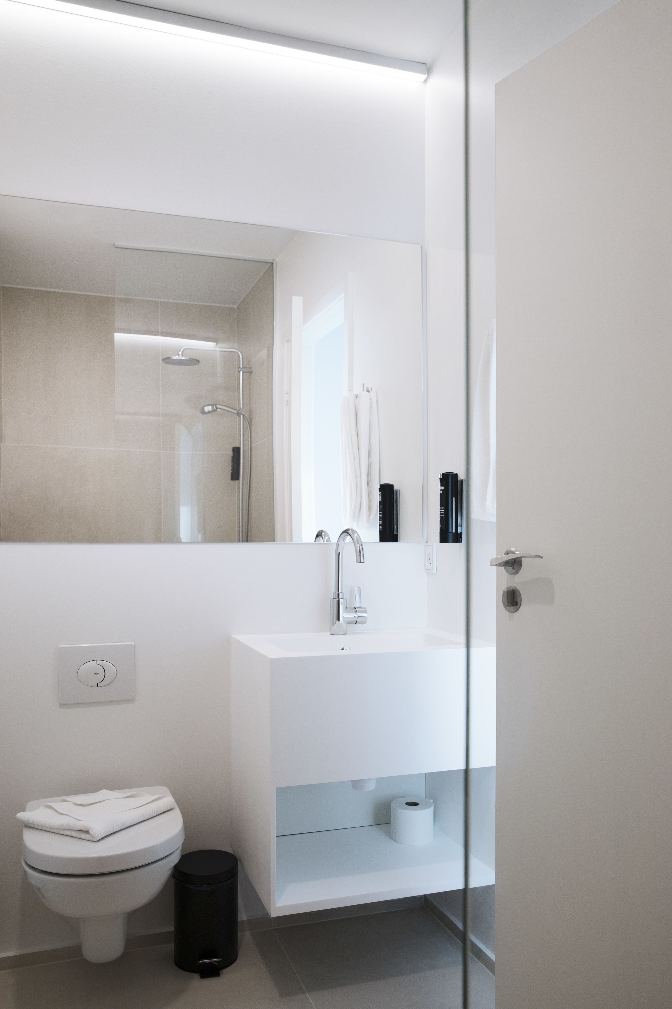 Un baño moderno con inodoro, lavamanos y espejo.