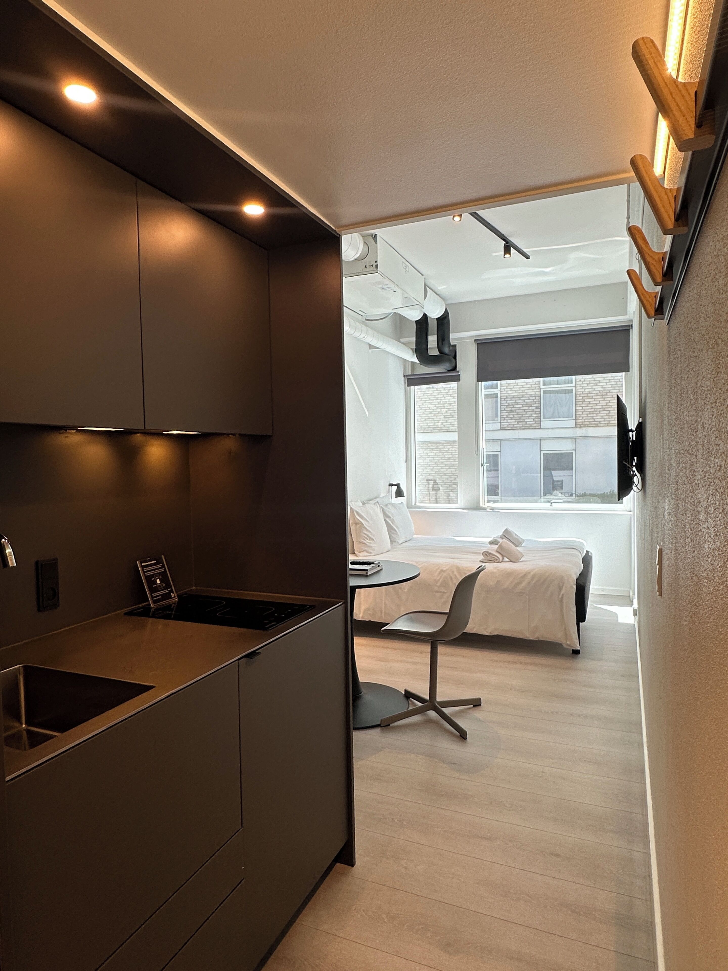 A modern kitchen with a built-in island, a dining area with a table and chairs, and a bedroom with a bed and window.