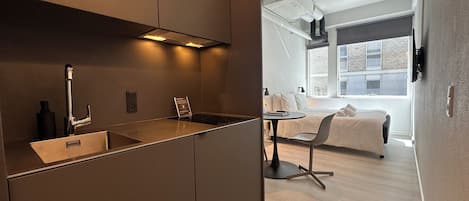 A modern kitchen with a built-in stove, a sink, and a small dining area with a table and chairs.