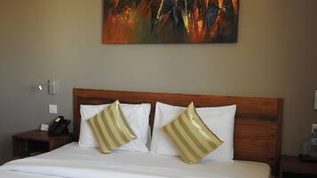 A hotel room with a wooden headboard, white bedding, and two striped pillows.