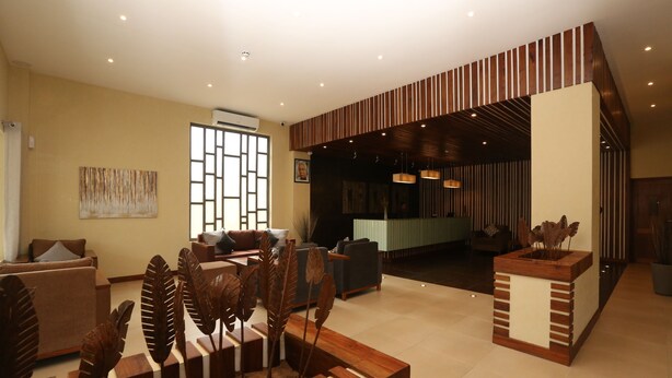 A spacious lobby with a modern reception desk, comfortable seating area, and decorative wooden plant sculptures. - Venus Premier Hotel (Arusha)