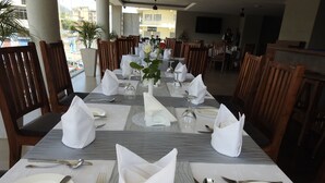 A dining area with tables set for four, each with white tablecloths, silverware, and glassware. - Venus Premier Hotel (Arusha)
