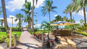 A wooden pathway leading to a bar area with outdoor seating, surrounded by palm trees and a clear sky. - The Residences on Siesta Key within Hyatt Residence Club (Siesta Key)