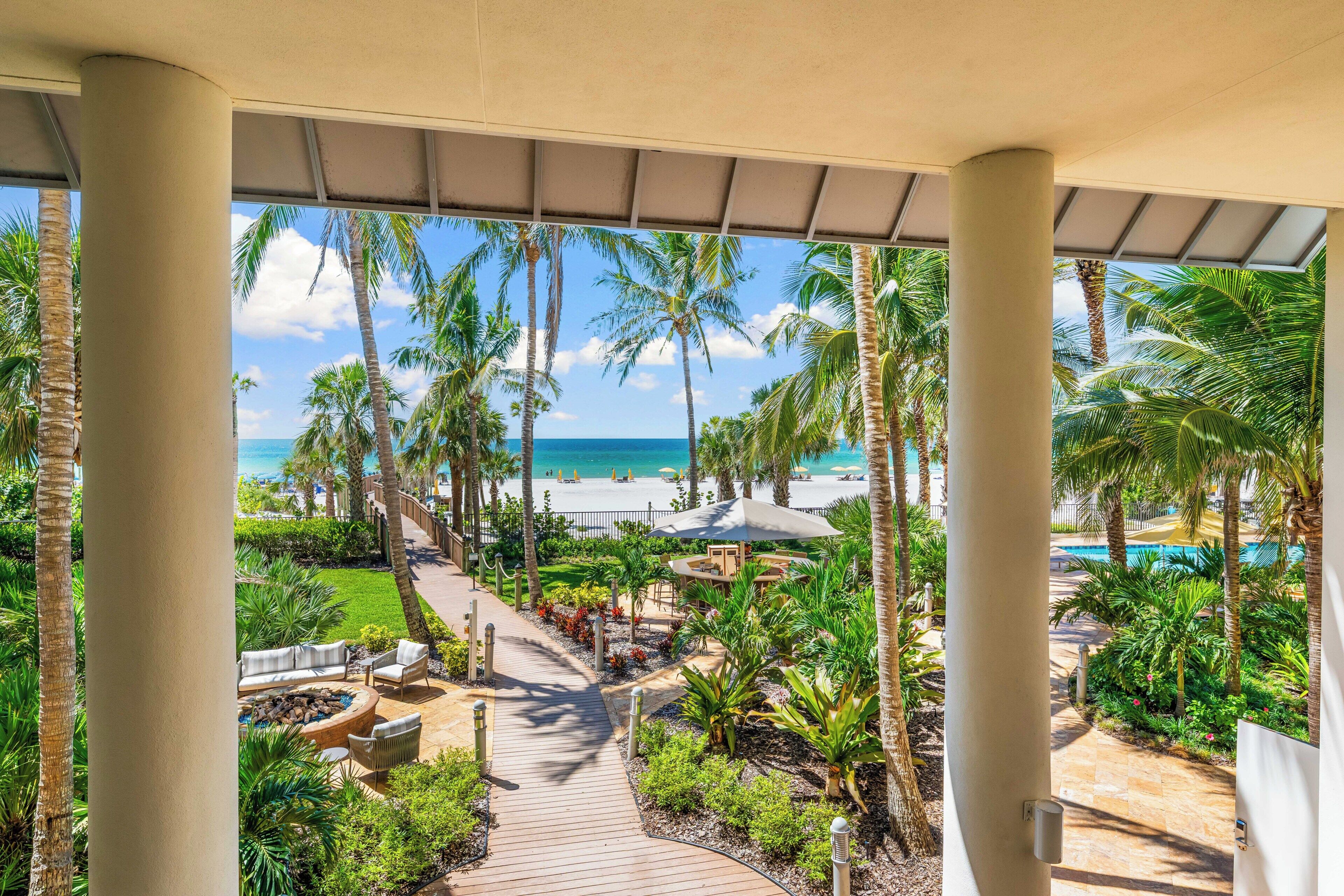 A covered outdoor area with a pathway leading to a pool and beach.